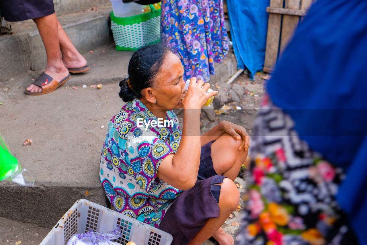 High angle view of woman drinking juice sitting at market