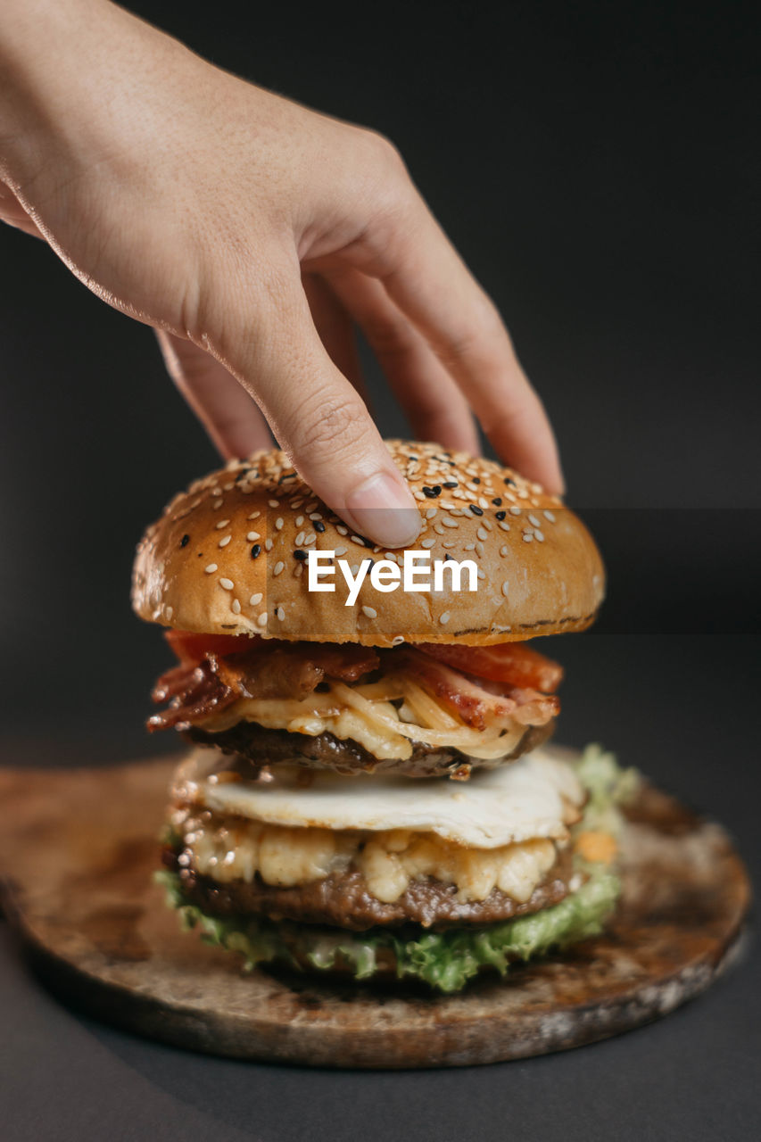 CLOSE-UP OF HAND HOLDING BURGER
