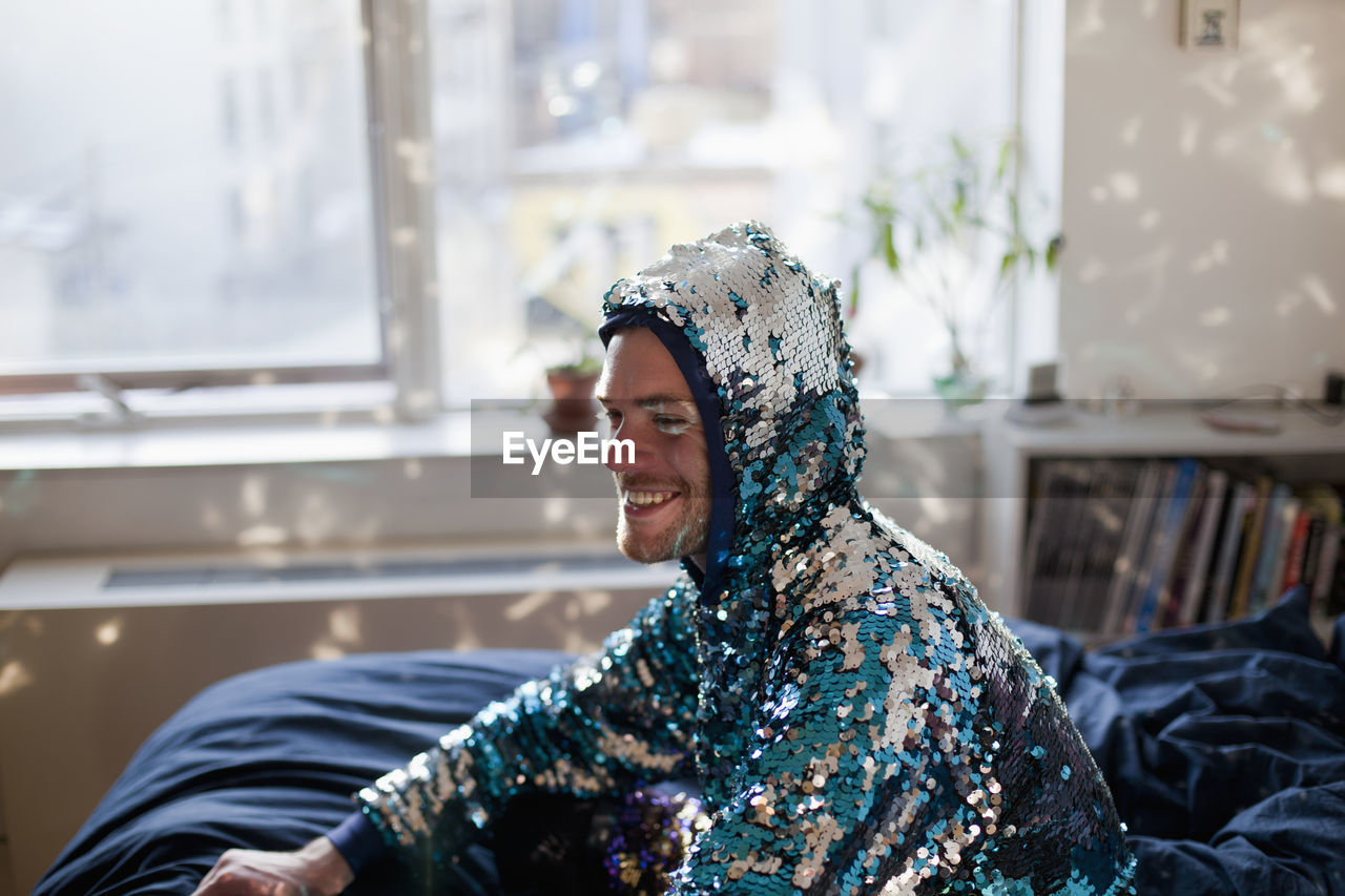 A man smiling in a sequin jacket
