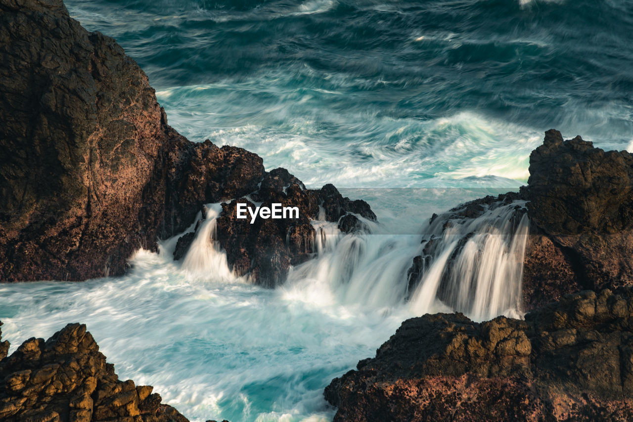 water, beauty in nature, rock, motion, sea, scenics - nature, coast, body of water, wave, land, ocean, waterfall, nature, surfing, wind wave, water sports, environment, sports, rock formation, long exposure, shore, cliff, power in nature, landscape, travel destinations, terrain, beach, outdoors, splashing, water feature, travel, tourism, idyllic