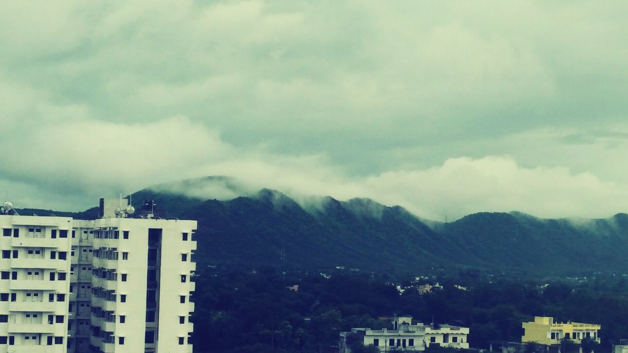HOUSES ON MOUNTAIN AGAINST CLOUDY SKY