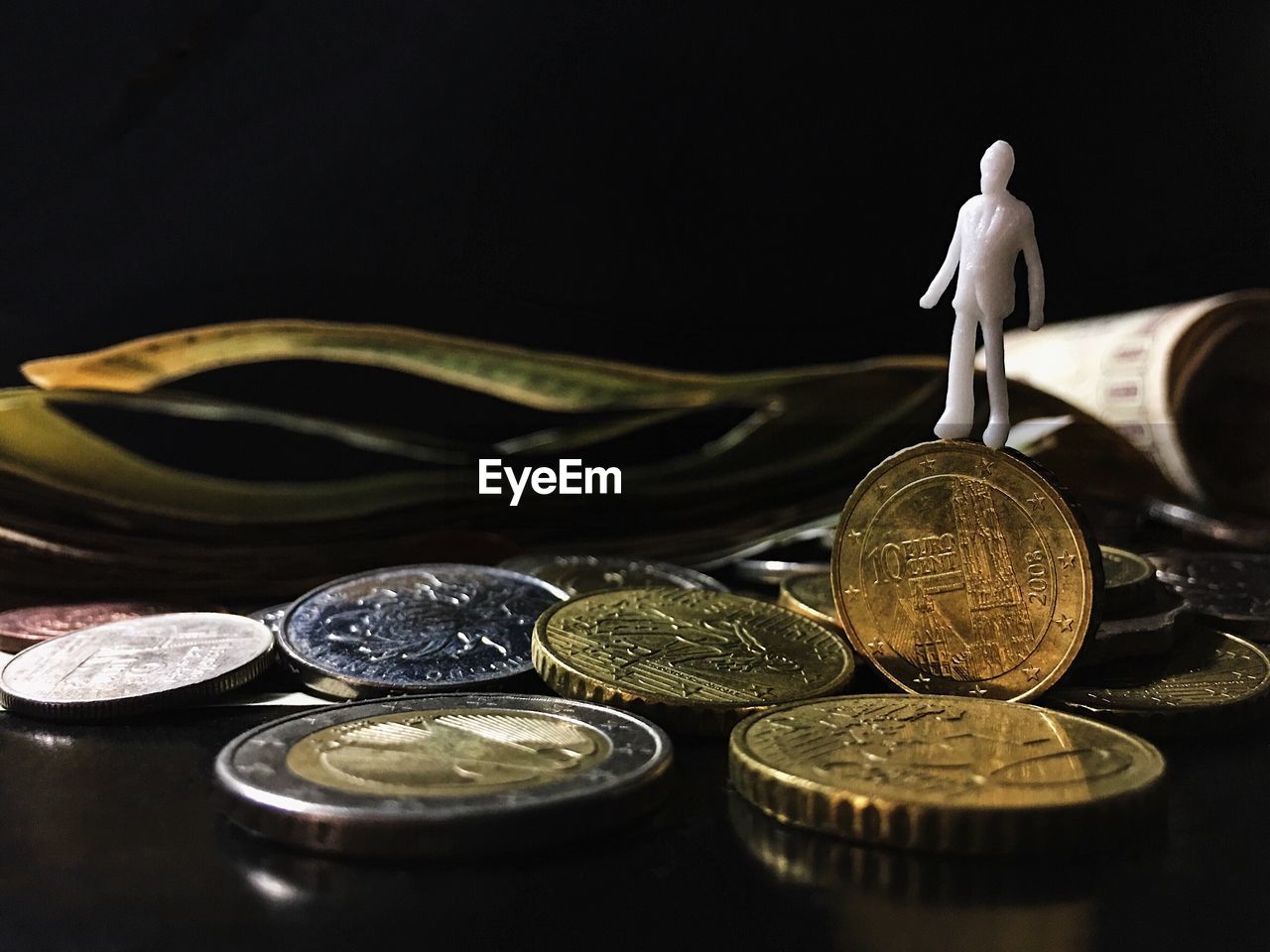 Close-up of coins and figurine against black background