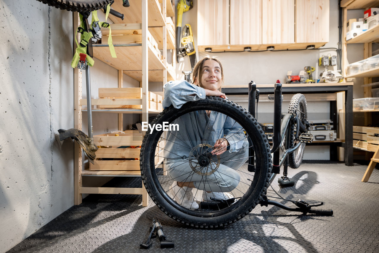 SIDE VIEW OF WOMAN WITH BICYCLE SITTING IN A ROW