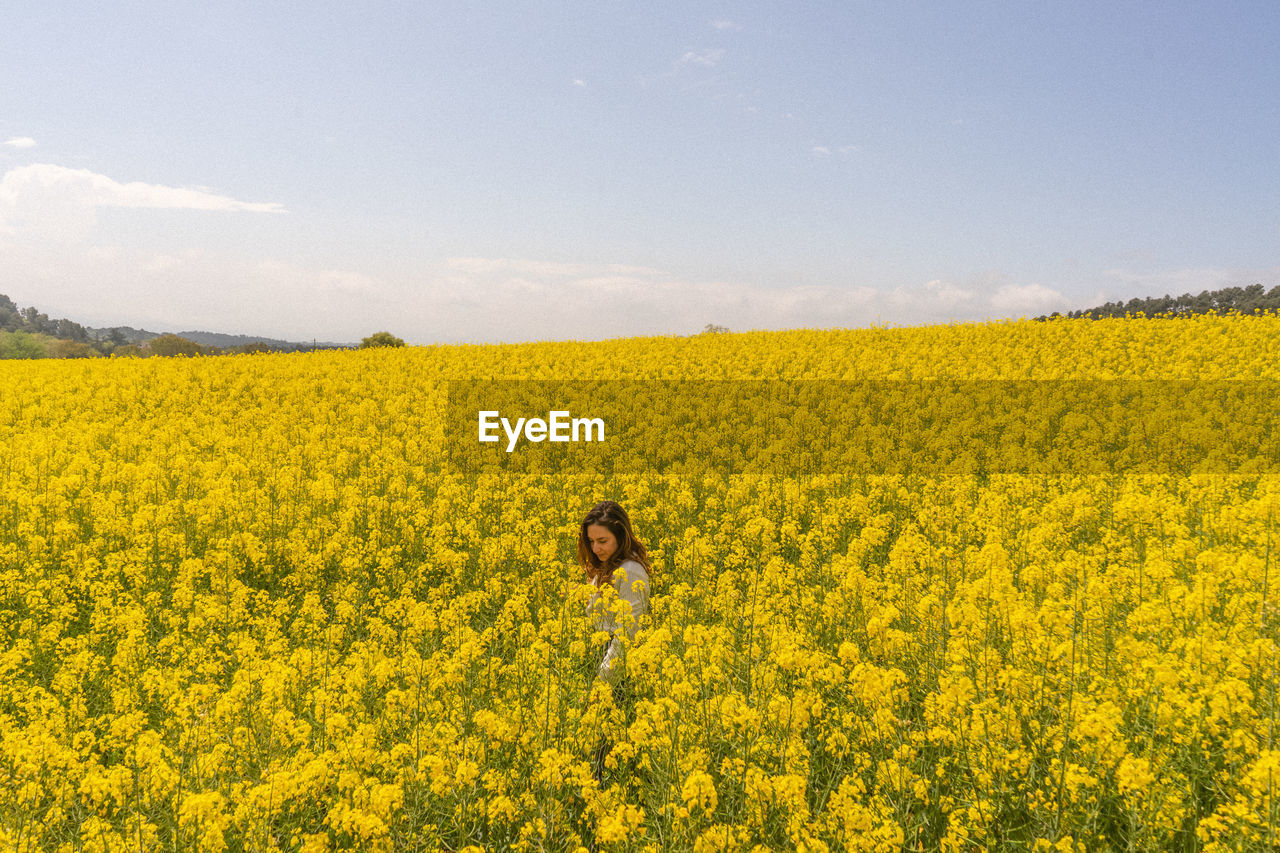 Scenic view of oilseed rape field against sky and a girl in the middle 