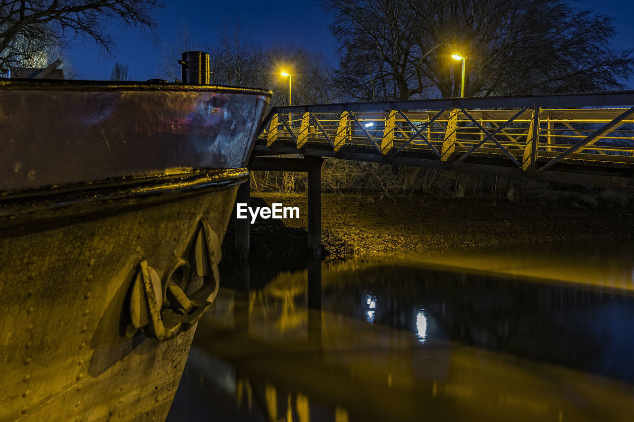 Boat in canal by footbridge at night