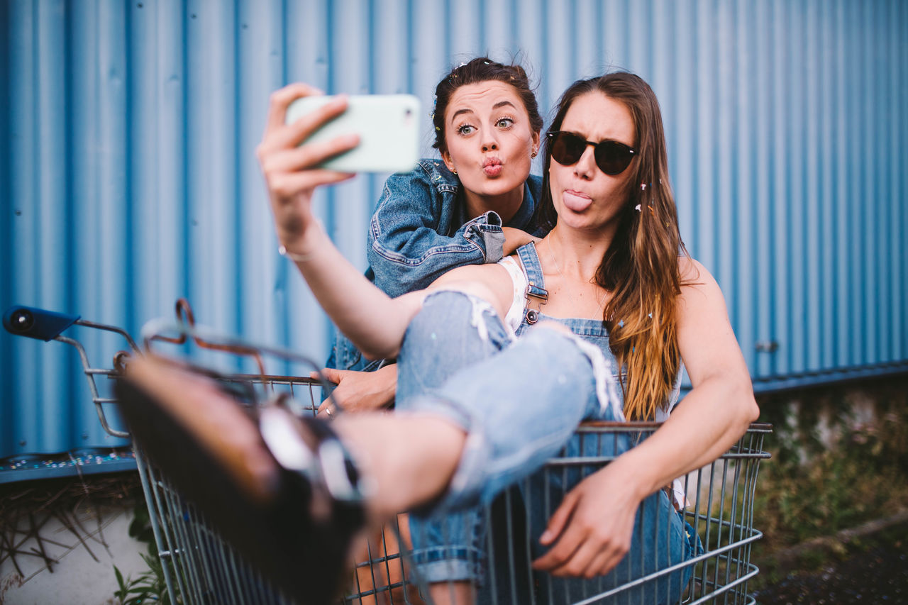 Friends making face while taking selfie through mobile phone