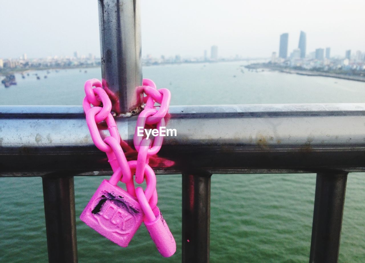 Close-up of pink padlocks on railing against water
