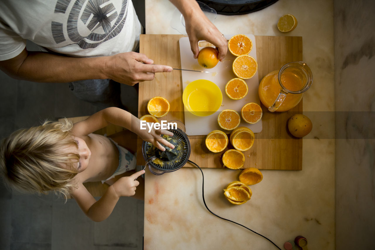 Boy making orange juice with father