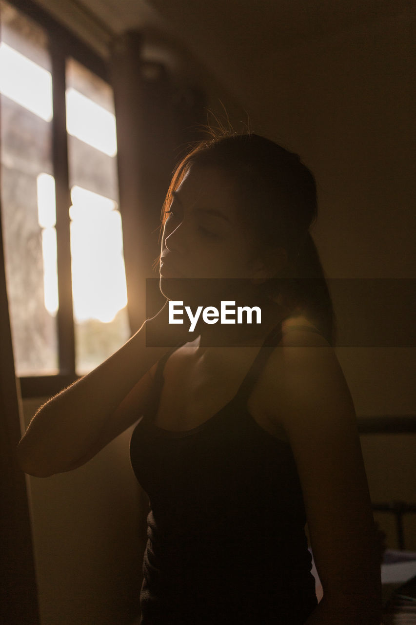 Young woman looking away by window at home