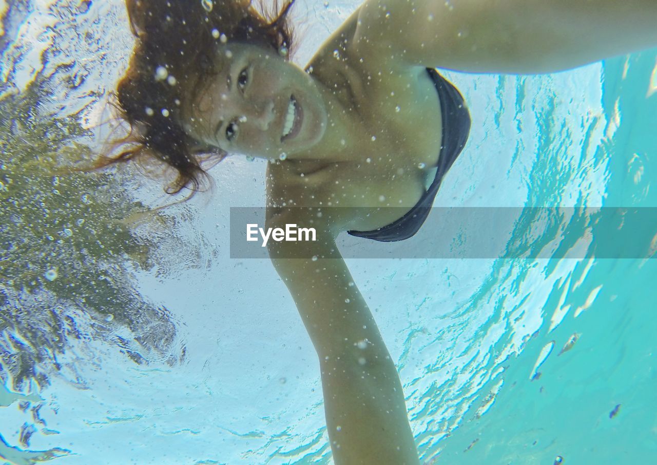 Low angle portrait of smiling woman swimming undersea