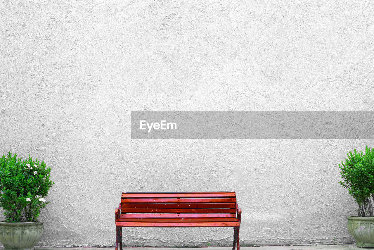 Empty red bench against white wall