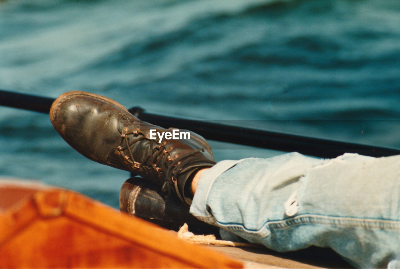 Low section of person wearing shoes sitting on boat deck