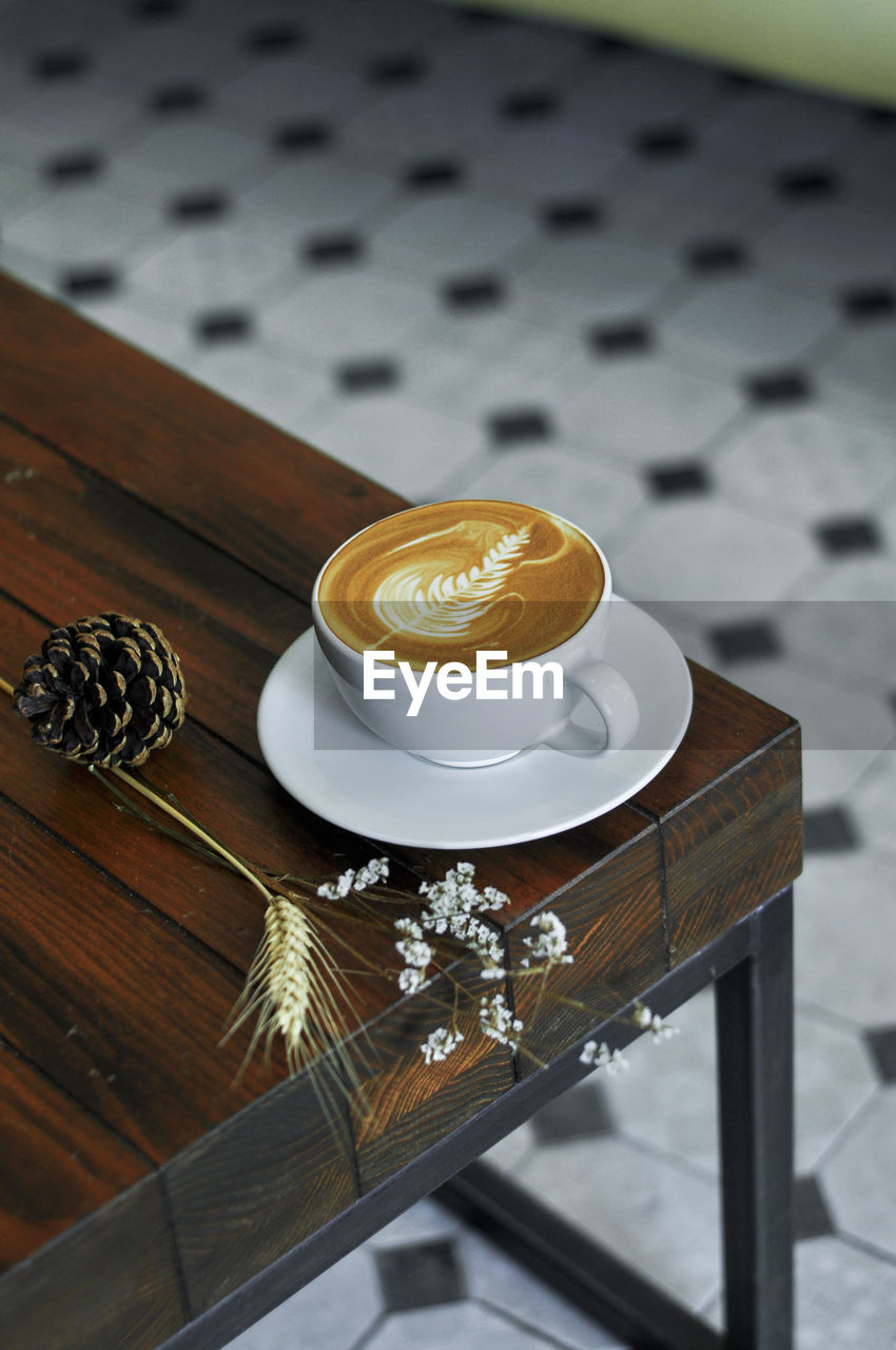 HIGH ANGLE VIEW OF COFFEE CUP ON TABLE AGAINST THE BACKGROUND