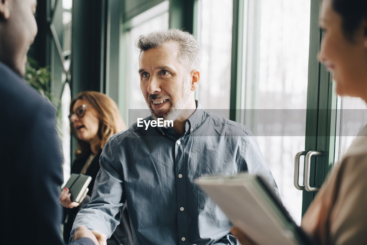 Mature businessman greeting young colleague in meeting at office