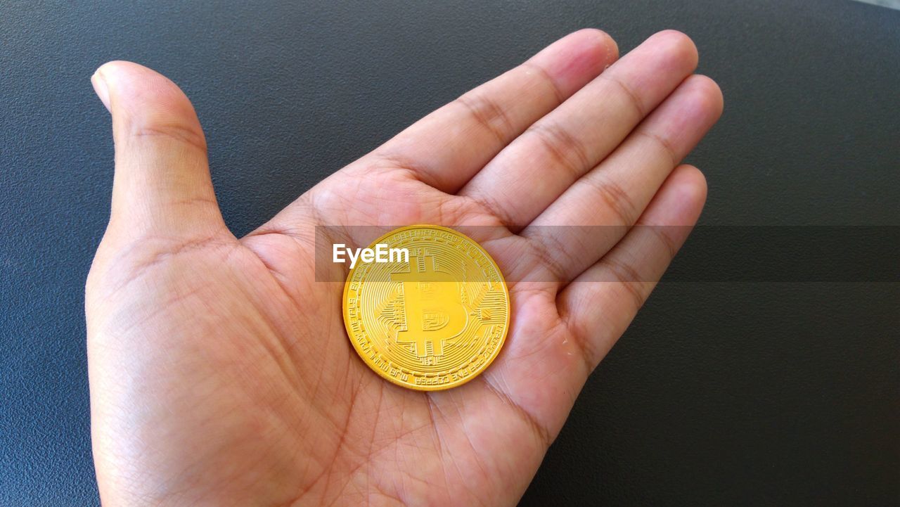 Cropped hand holding bitcoin over table