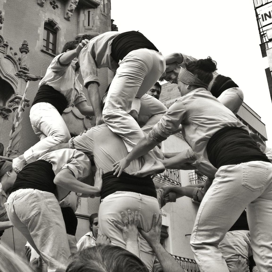 Low angle view of people making castellers against clear sky