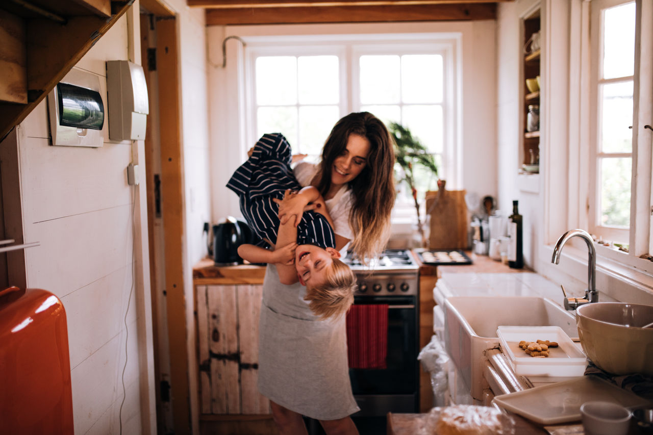 Mother playing with cute son in kitchen at home