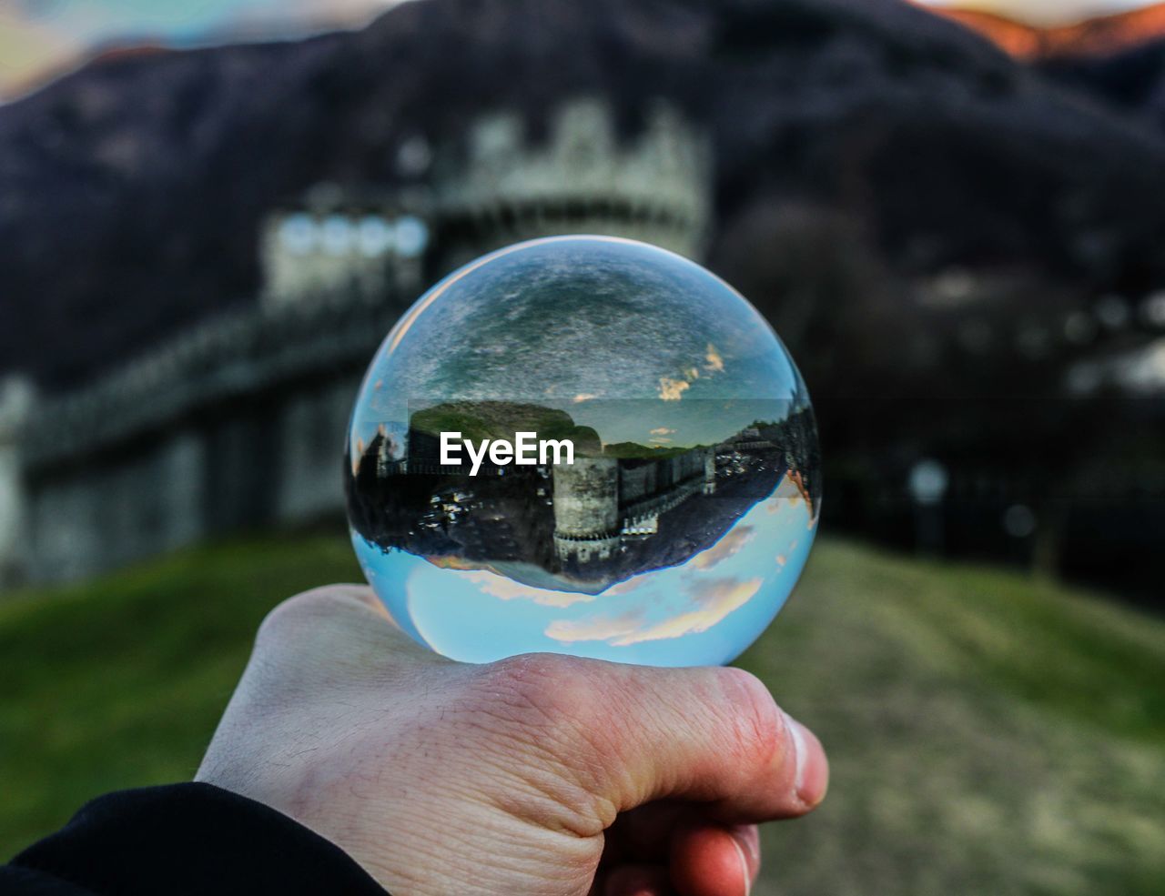 Cropped hand holding crystal ball with reflection of palace