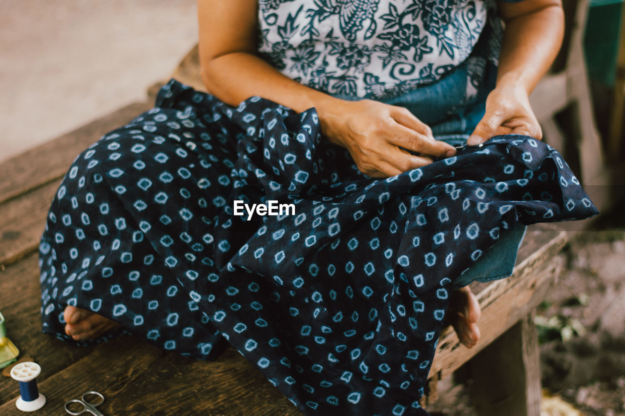 Midsection of woman knitting cloth