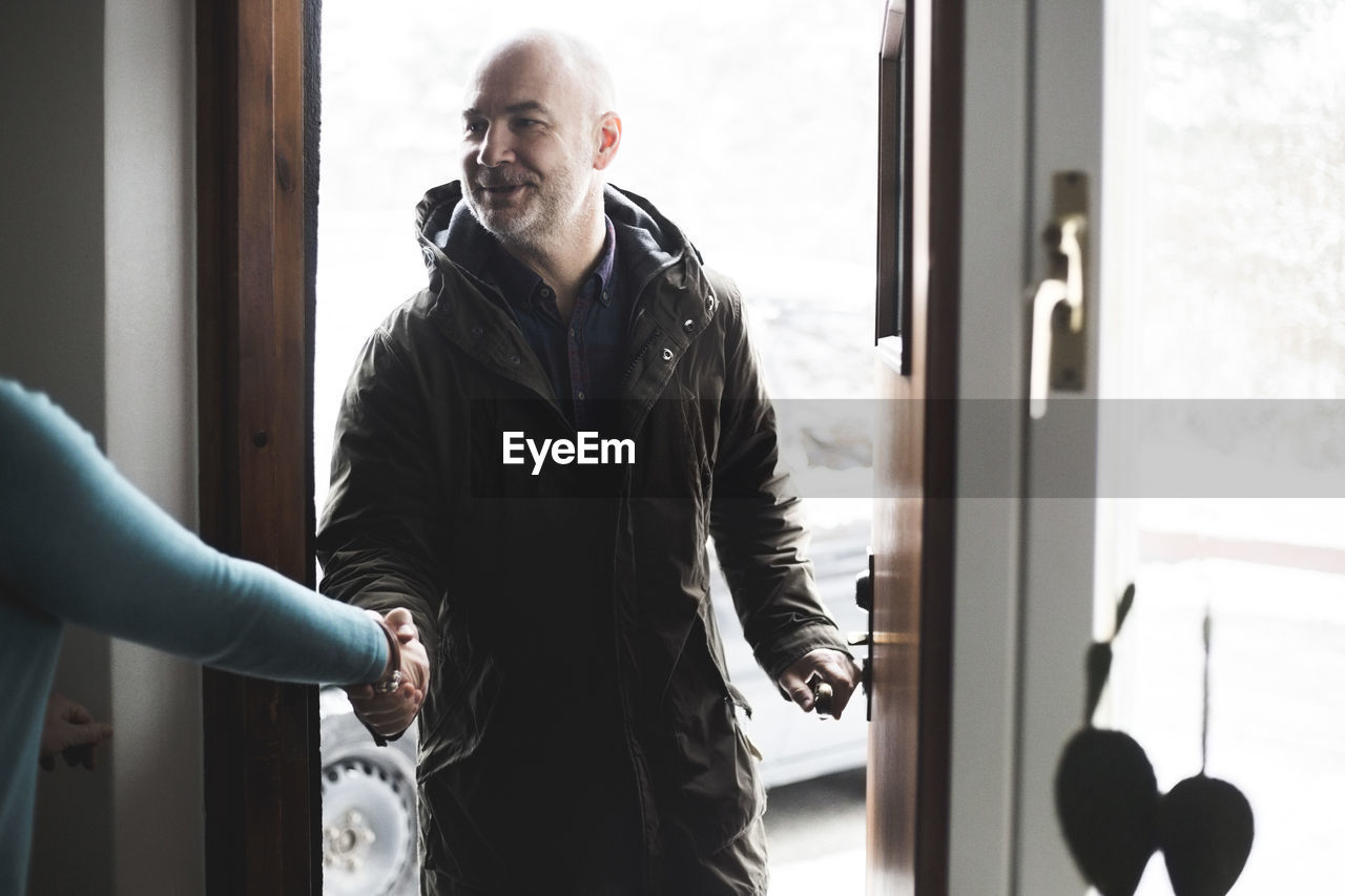 Mature man shaking hands with doctor at open doorway