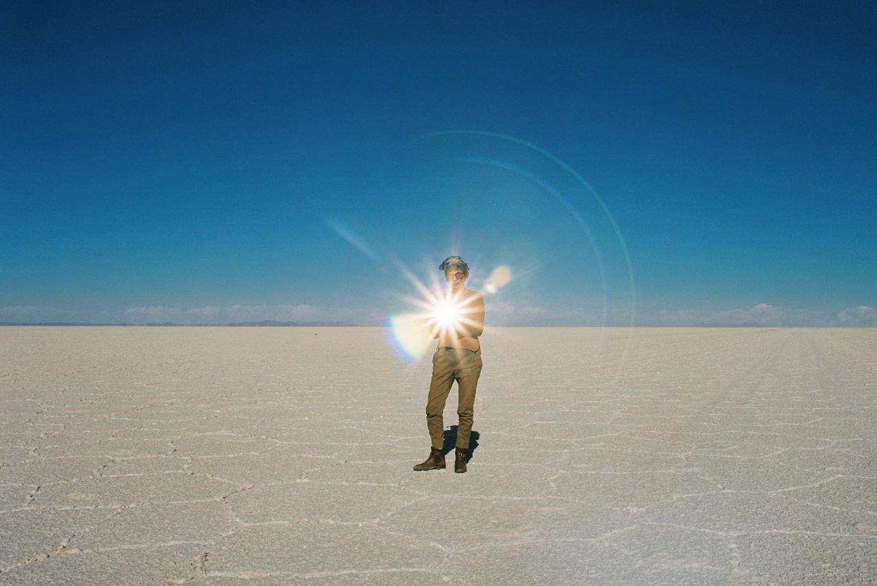 Man standing on salt flat against clear blue sky