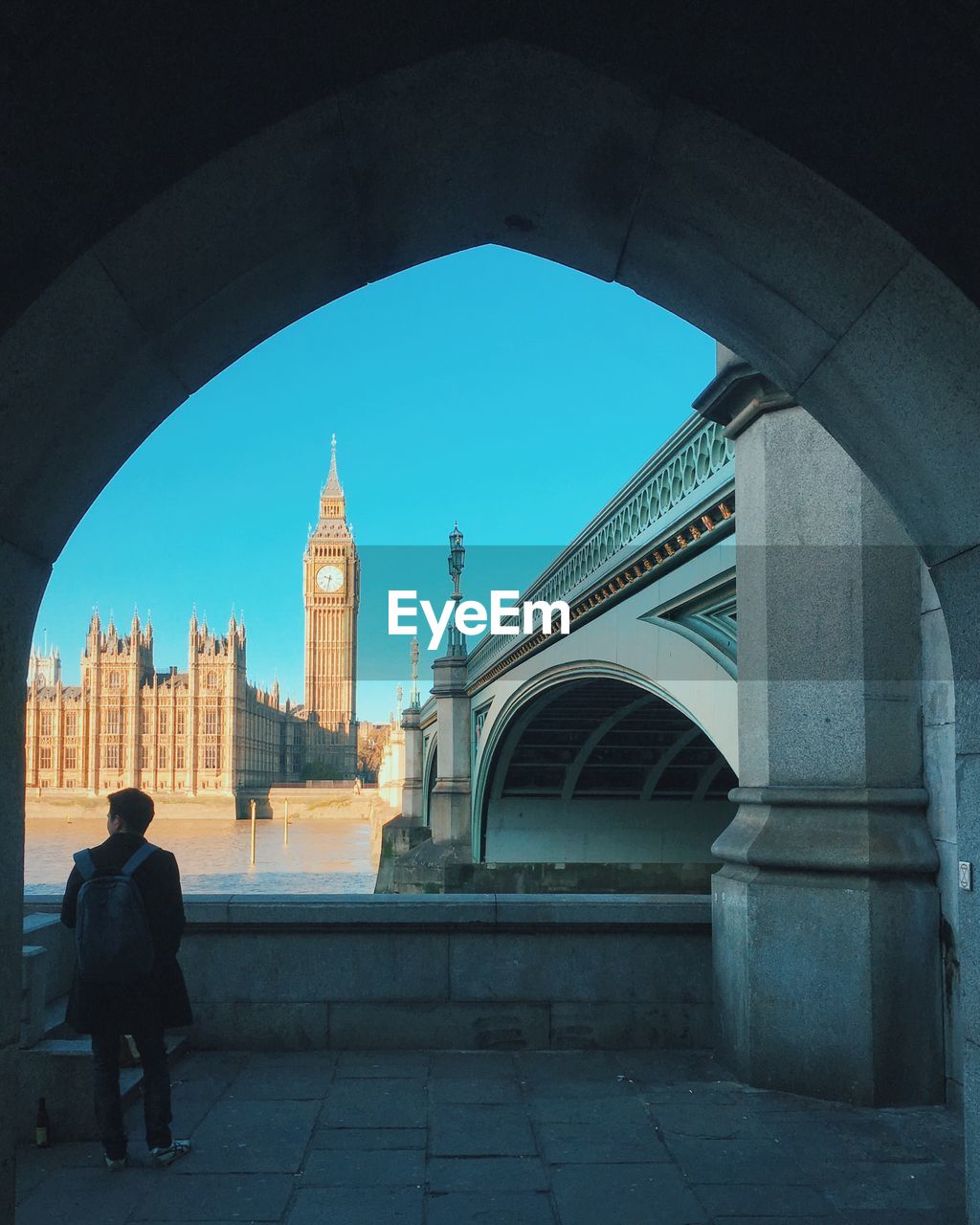 Rear view of man standing against big ben seen through arch in city