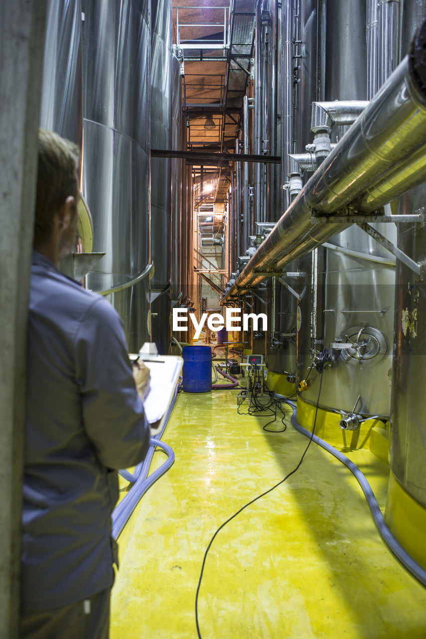 Worker controlling stainless steel tanks for food industry