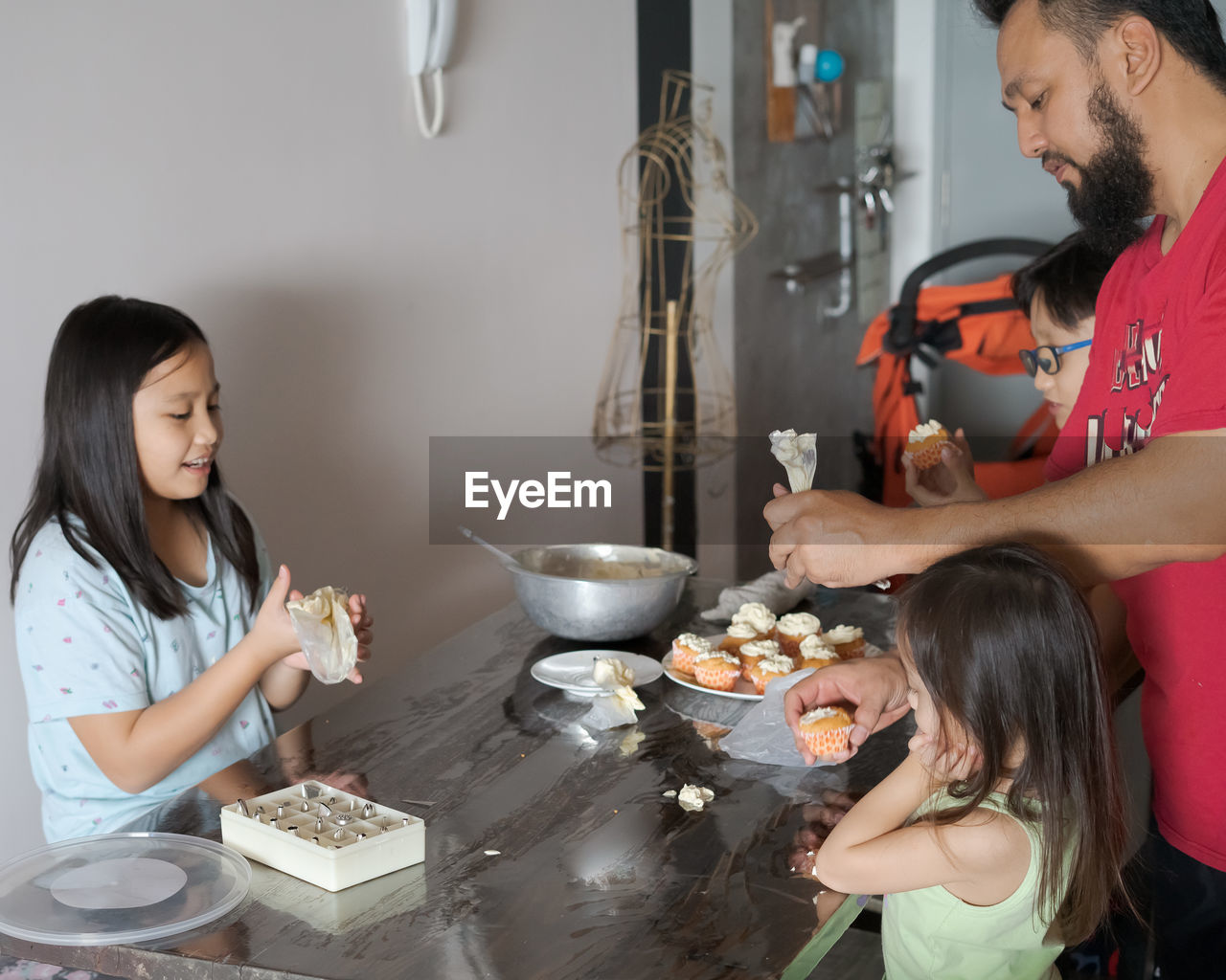 Father with children making sweet food on table at home