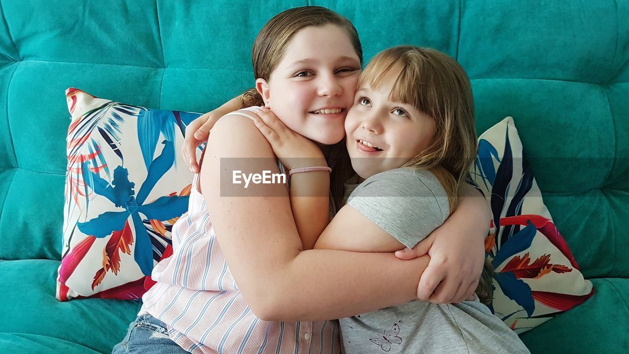 Portrait of cute overweight girl embracing sister at home