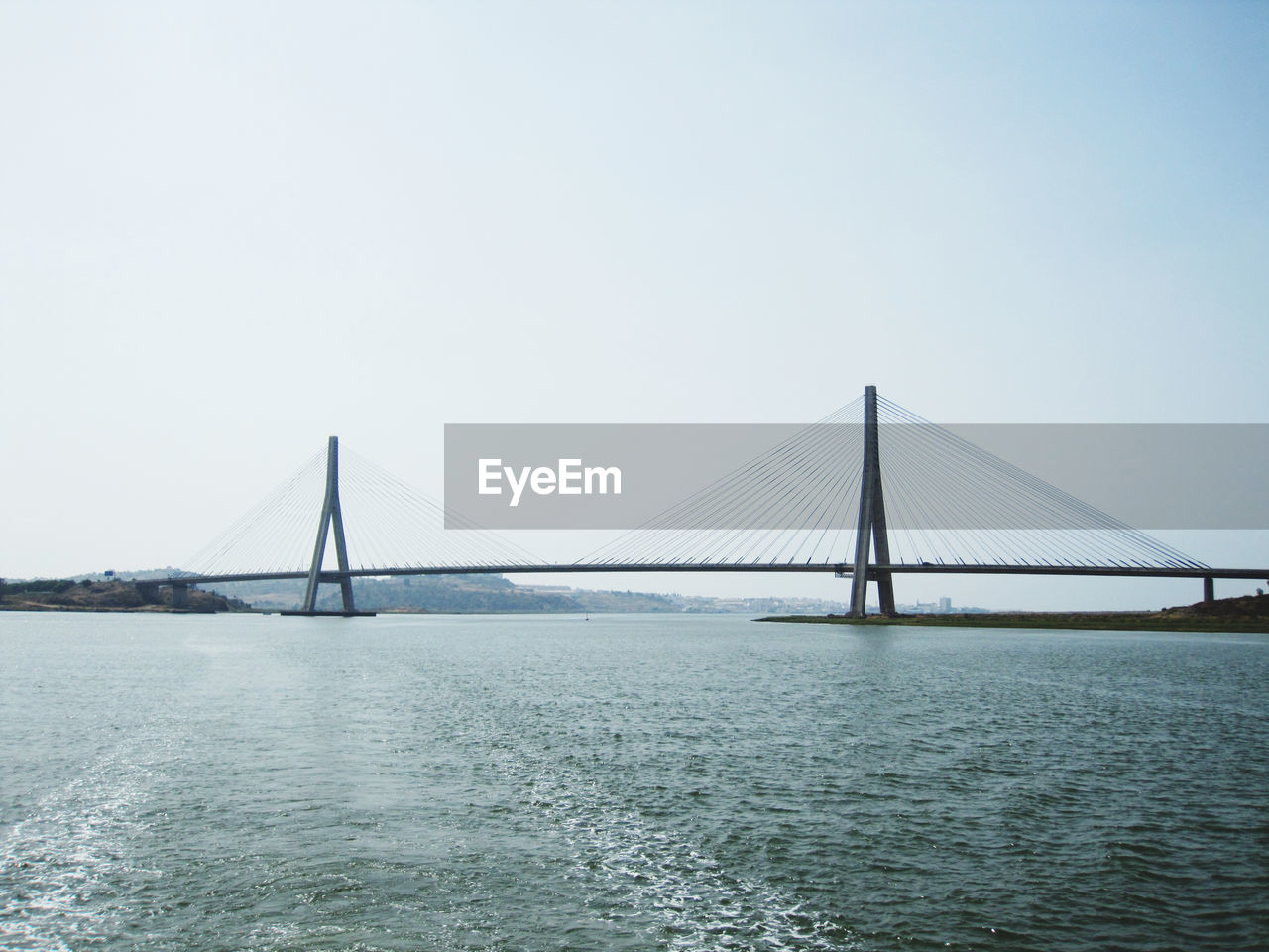 Suspension bridge over sea against clear sky