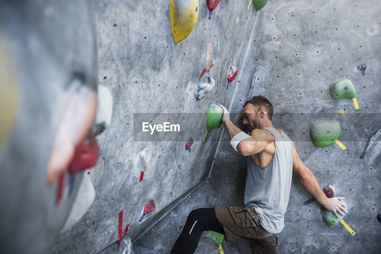 Determined athlete climbing on rock wall at gym