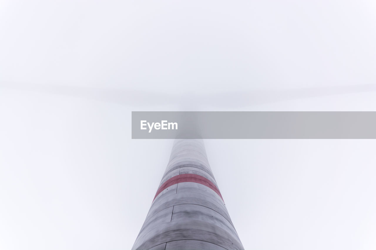 Low angle view of wind turbine in foggy weather
