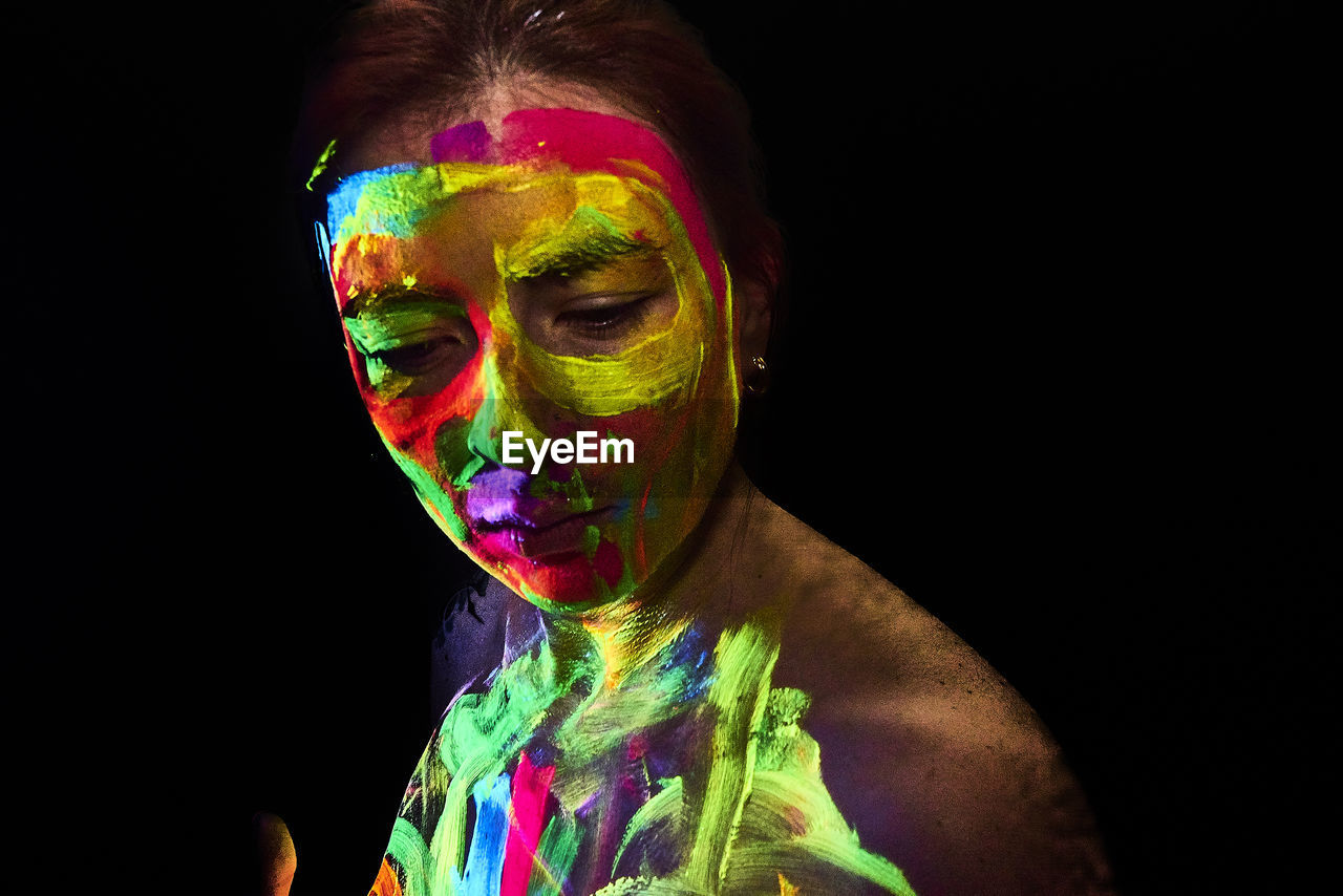 Woman with multi colored body paint against black background