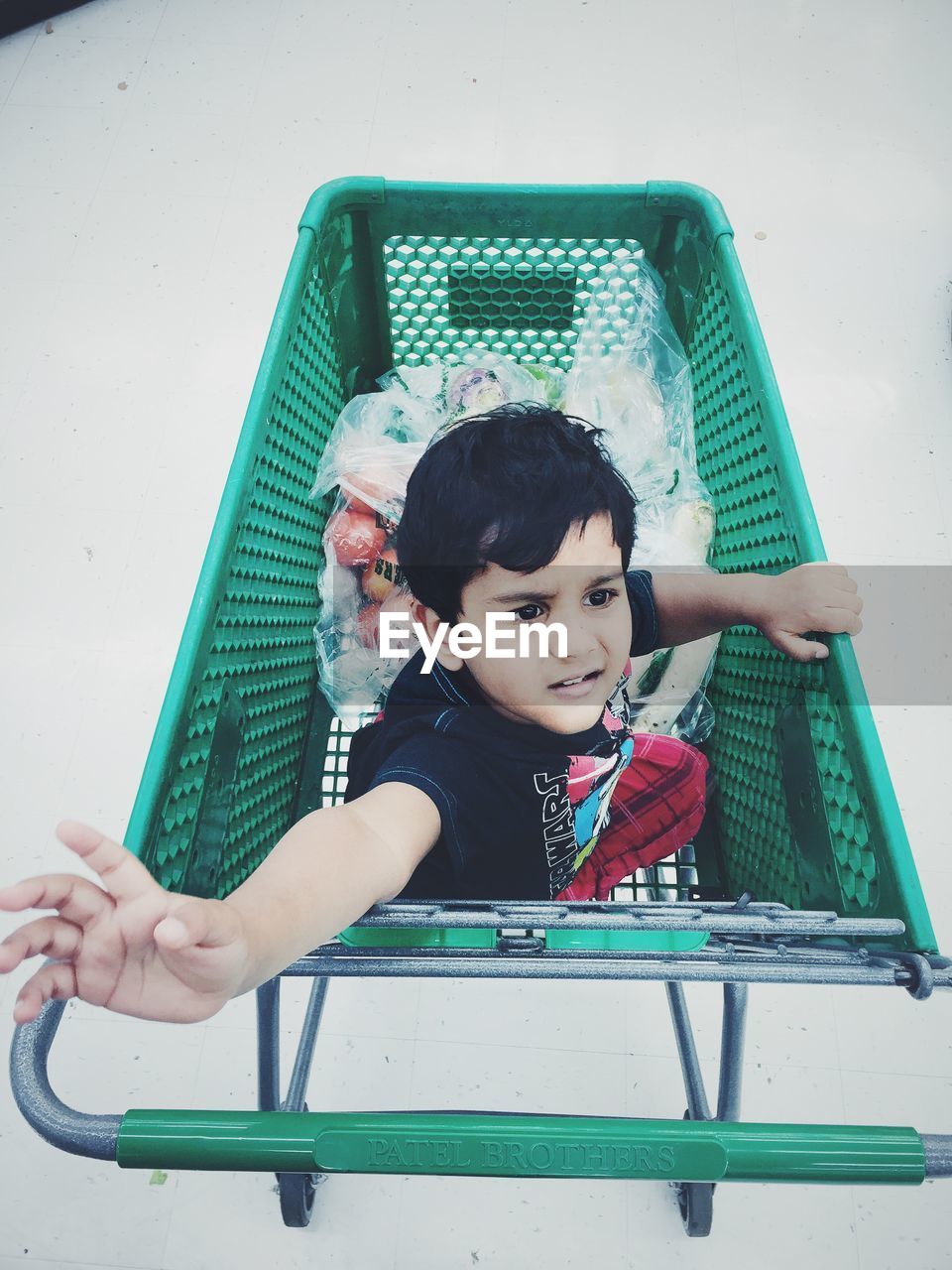 High angle view of boy sitting on shopping cart