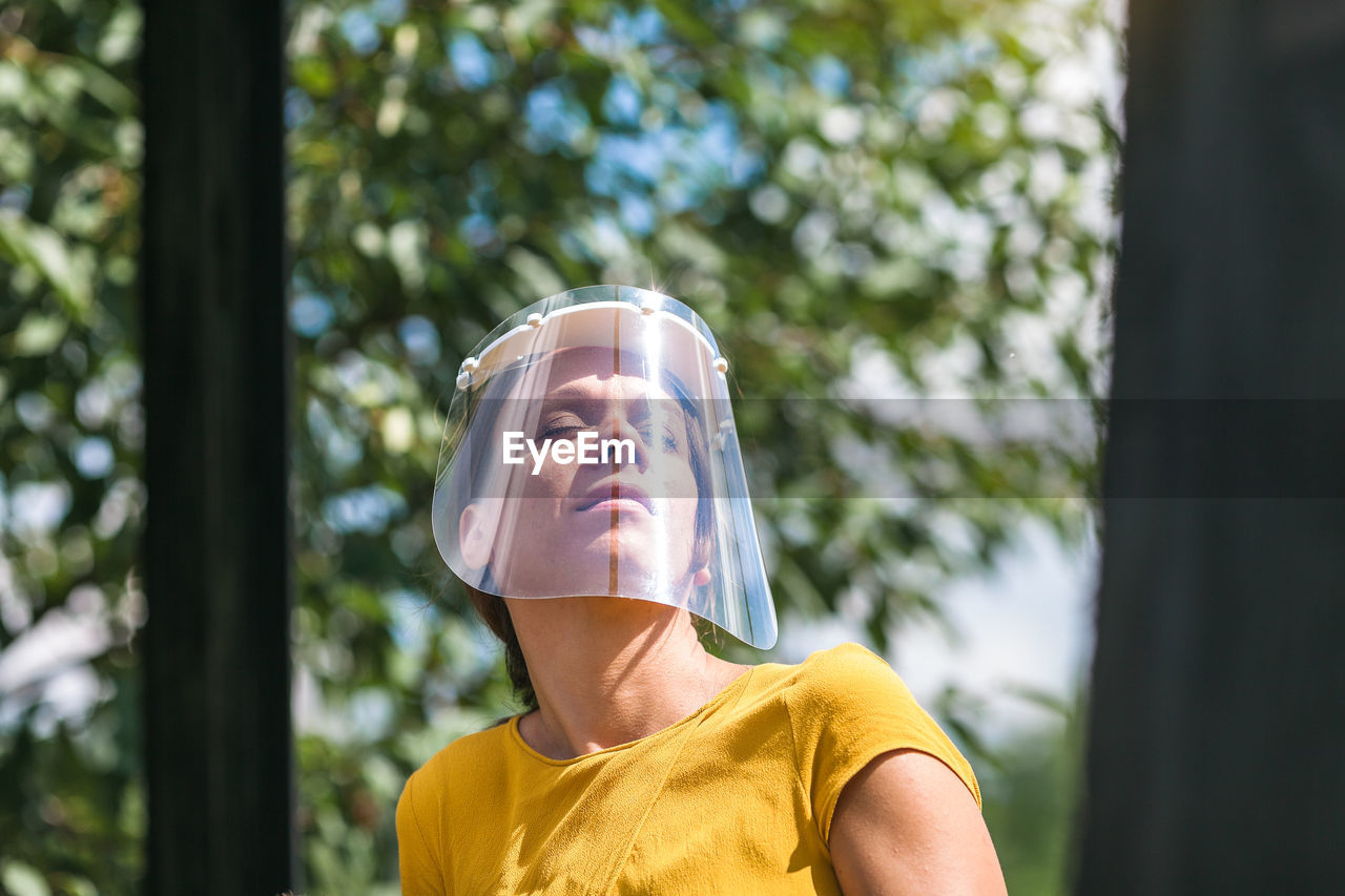 Close-up of woman wearing face shield against trees
