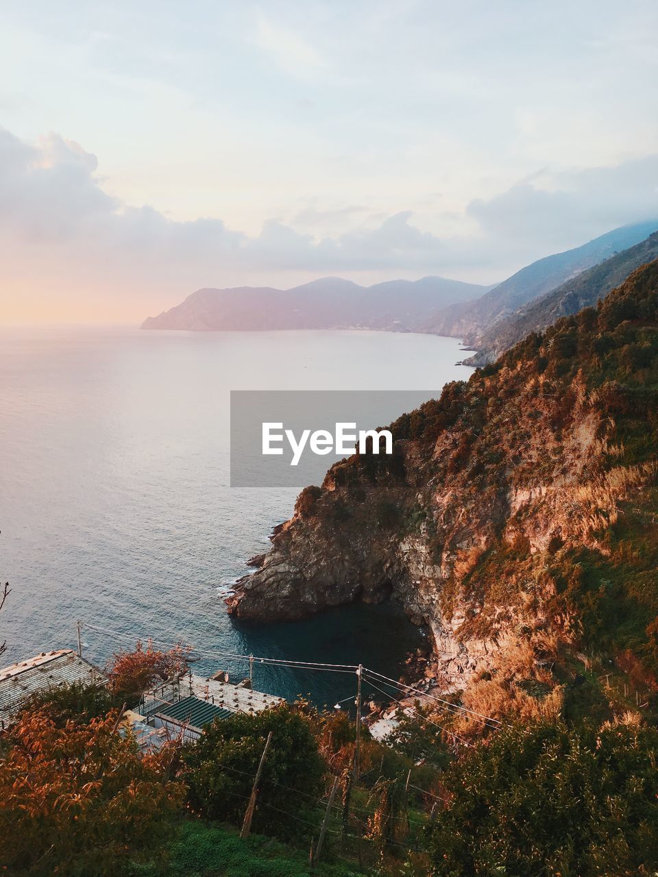 Scenic view of mountains on coastline against sky during sunset