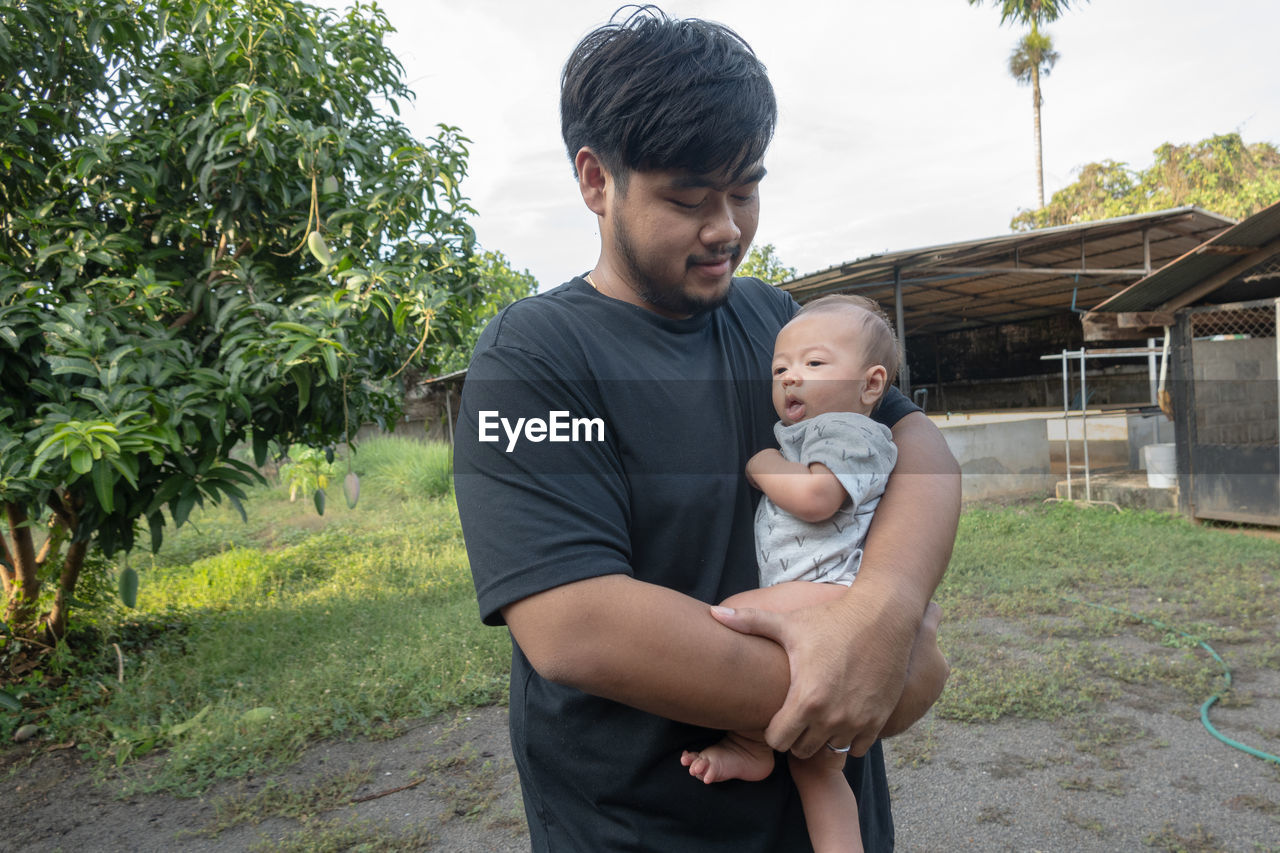 A young asian man holds a half-asian baby