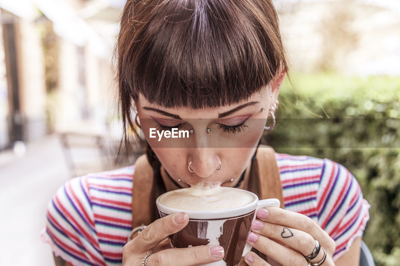 Close-up of young woman drinking coffee at outdoor cafe