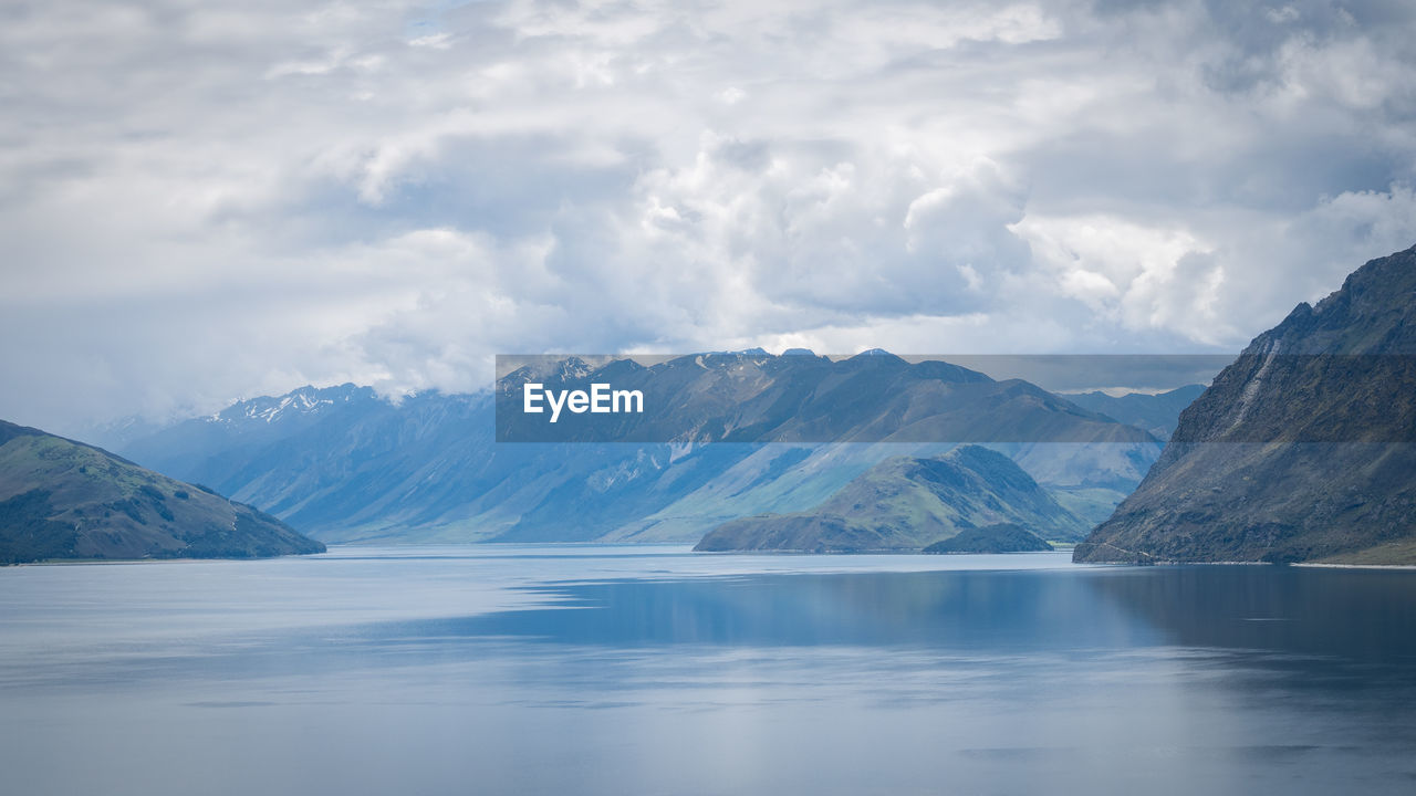 Scenic alpine lake surrounded by mountains shot on sunny day. location is lake hawea, new zealand