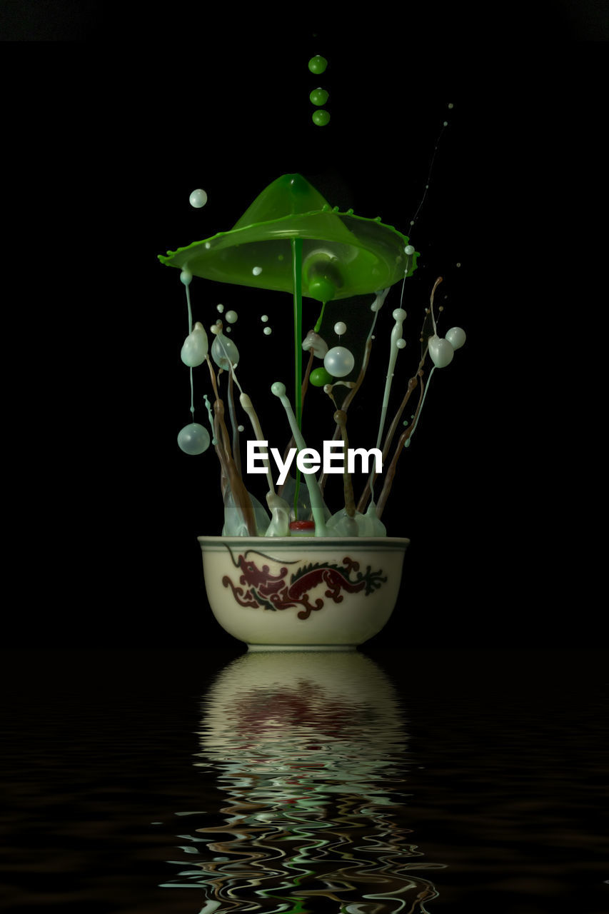Close-up of splashing liquid in bowl against black background