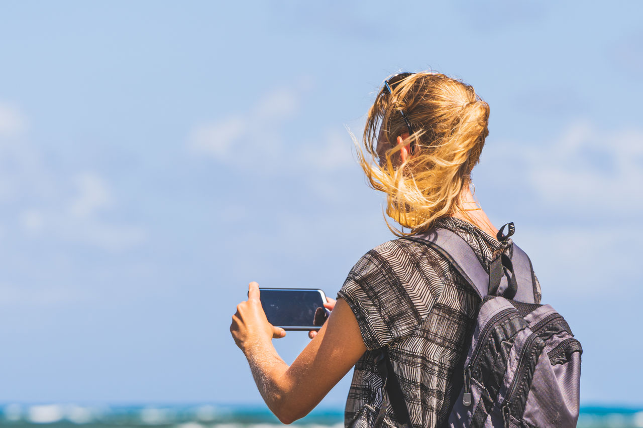 low angle view of young woman looking away against sky