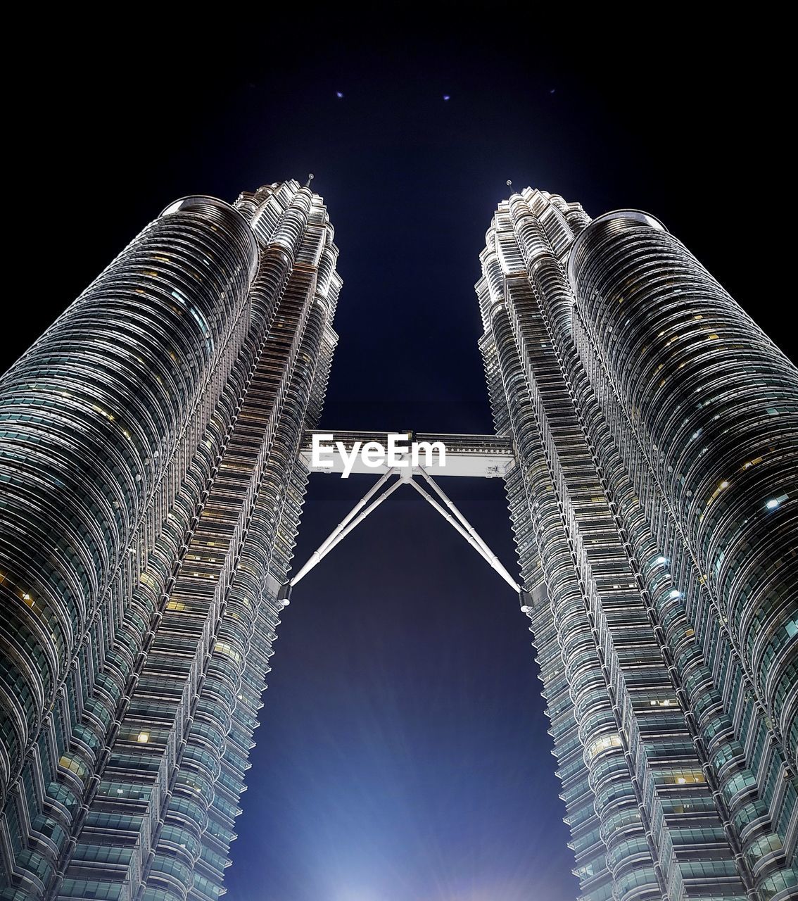 Low angle view of illuminated petronas towers against sky at night