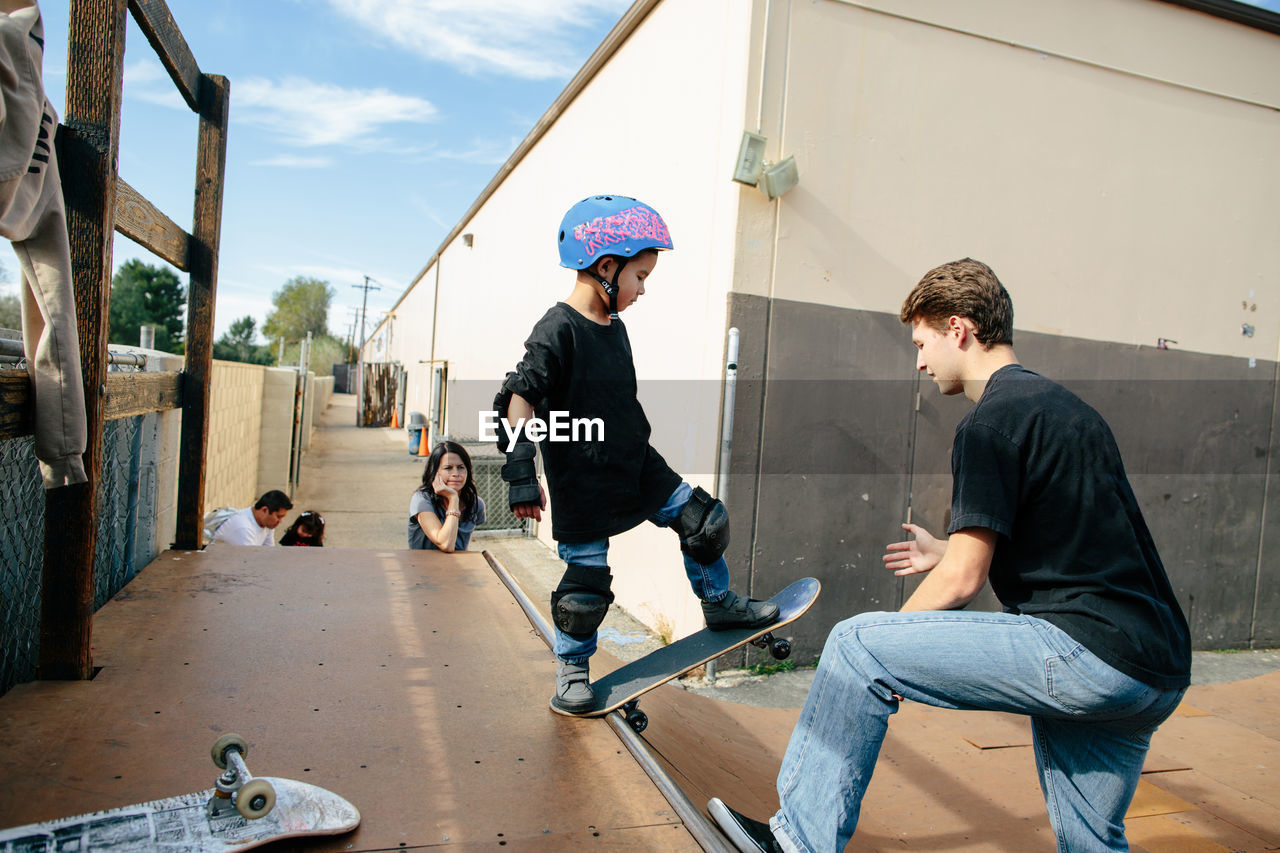 Kid about to go down half pipe with teacher's help