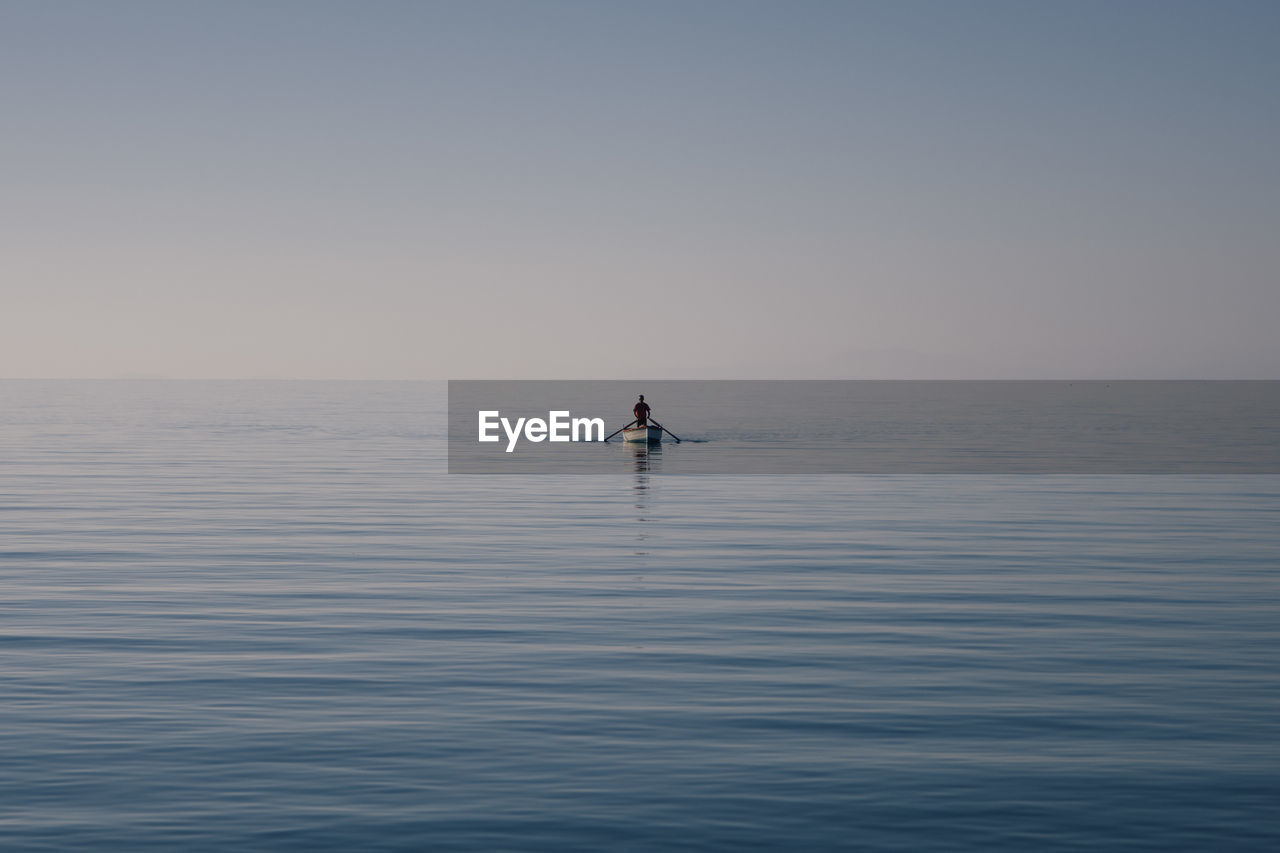 Man on boat sailing in sea against clear sky
