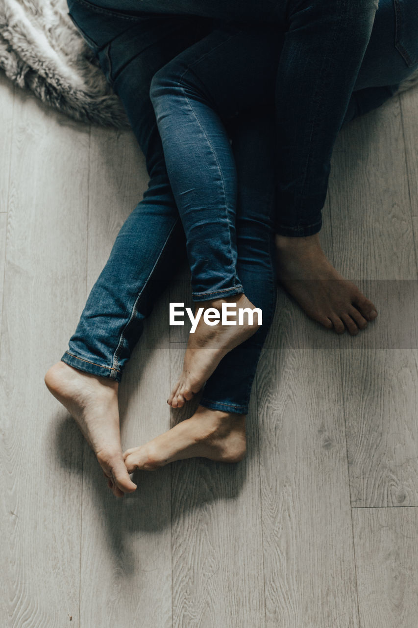 Low section of couple hugging on hardwood floor