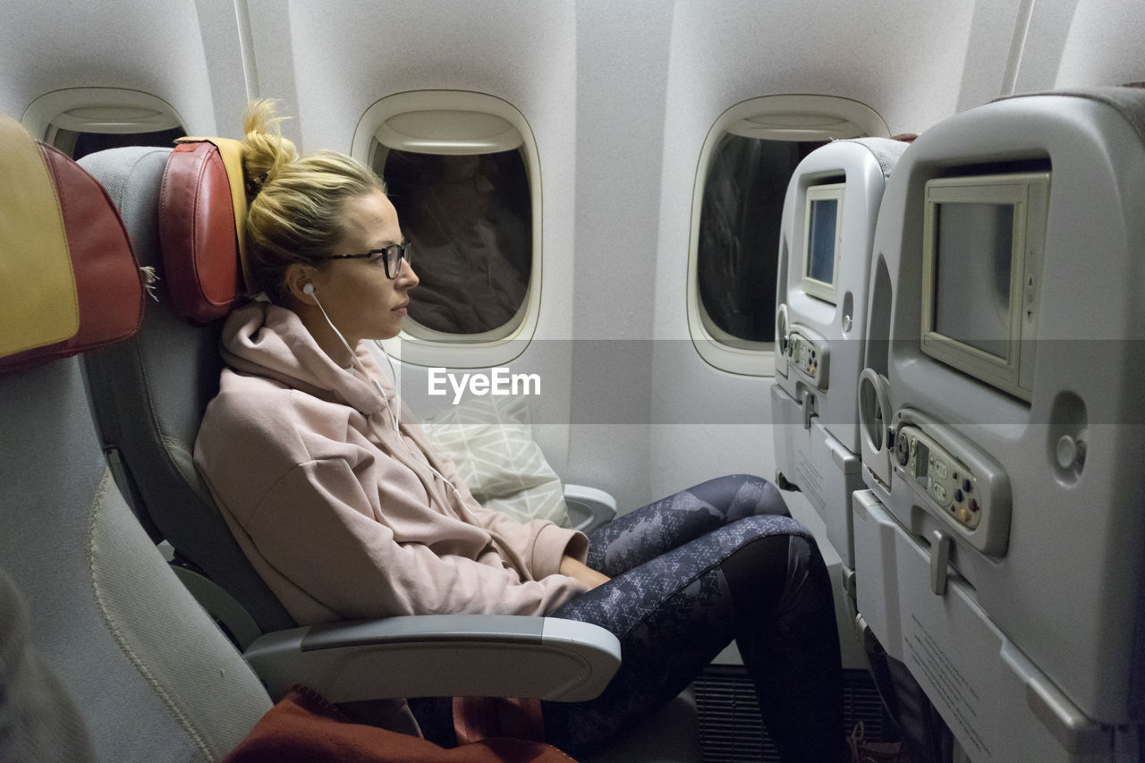 Side view of woman sitting in airplane