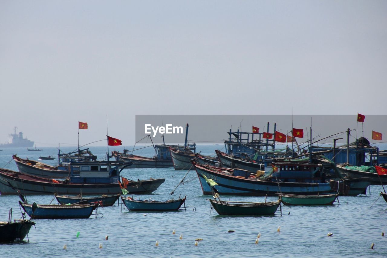 BOATS MOORED IN SEA AGAINST CLEAR SKY