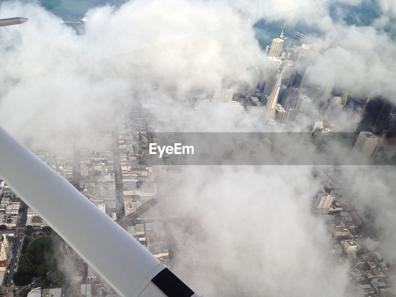 Cropped image of airplane over clouds covering cityscape