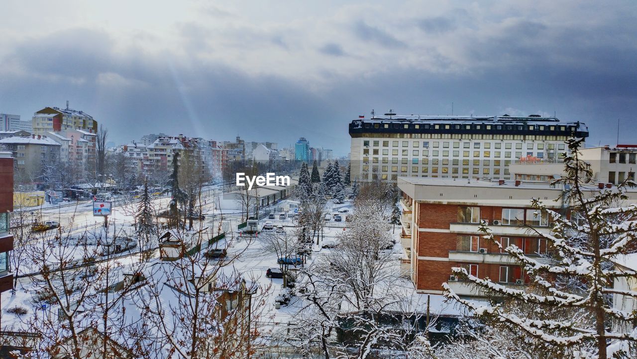 High angle view of street and buildings during winter against cloudy sky