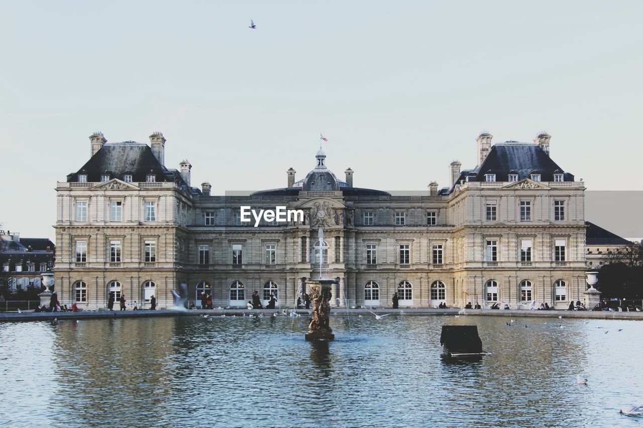 Pond by luxembourg palace against clear sky